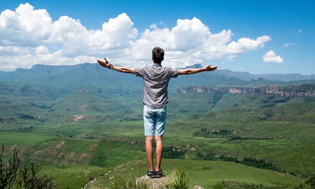 Man op bergtop met gespreide armen, straalt zelfliefde, vrijheid en innerlijke kracht uit.