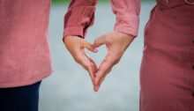 Twee mensen vormen samen een hart met hun handen als teken van verbondenheid en liefde.