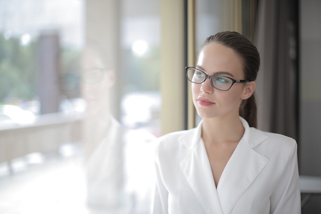 Jonge vrouw kijkt peinzend en bedachtzaam uit het raam, reflecterend op haar gevoelens en verwachtingen na een ontmoeting met haar ex.