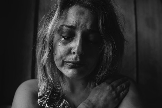 Close-up van een vrouw met betraand gezicht, die haar verdriet en kwetsbaarheid toont.