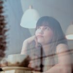 Vrouw die nadenkt en verlangend uit het raam kijkt in een café