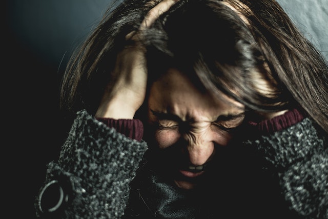Vrouw schreeuwt met handen in het haar, overweldigd door de emoties na een gebroken hart.