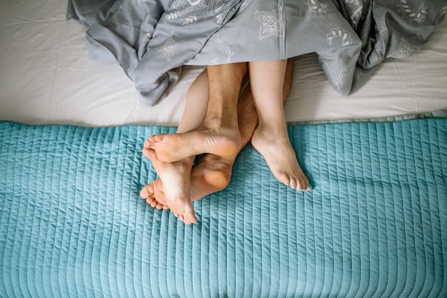 Twee paar voeten steken onder een dekbed uit. Friends with benefits of een one-night-stand?