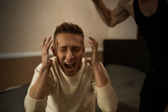 Man schreeuwt met handen bij zijn hoofd, symbool voor de emotionele uitbarstingen die je ex afschrikken na een relatiebreuk.
